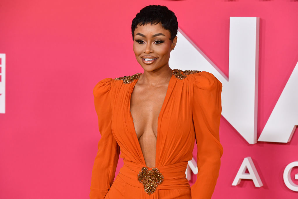 Blac Chyna at an event with very short hair and wearing a long-sleeved dress with a plunging neckline