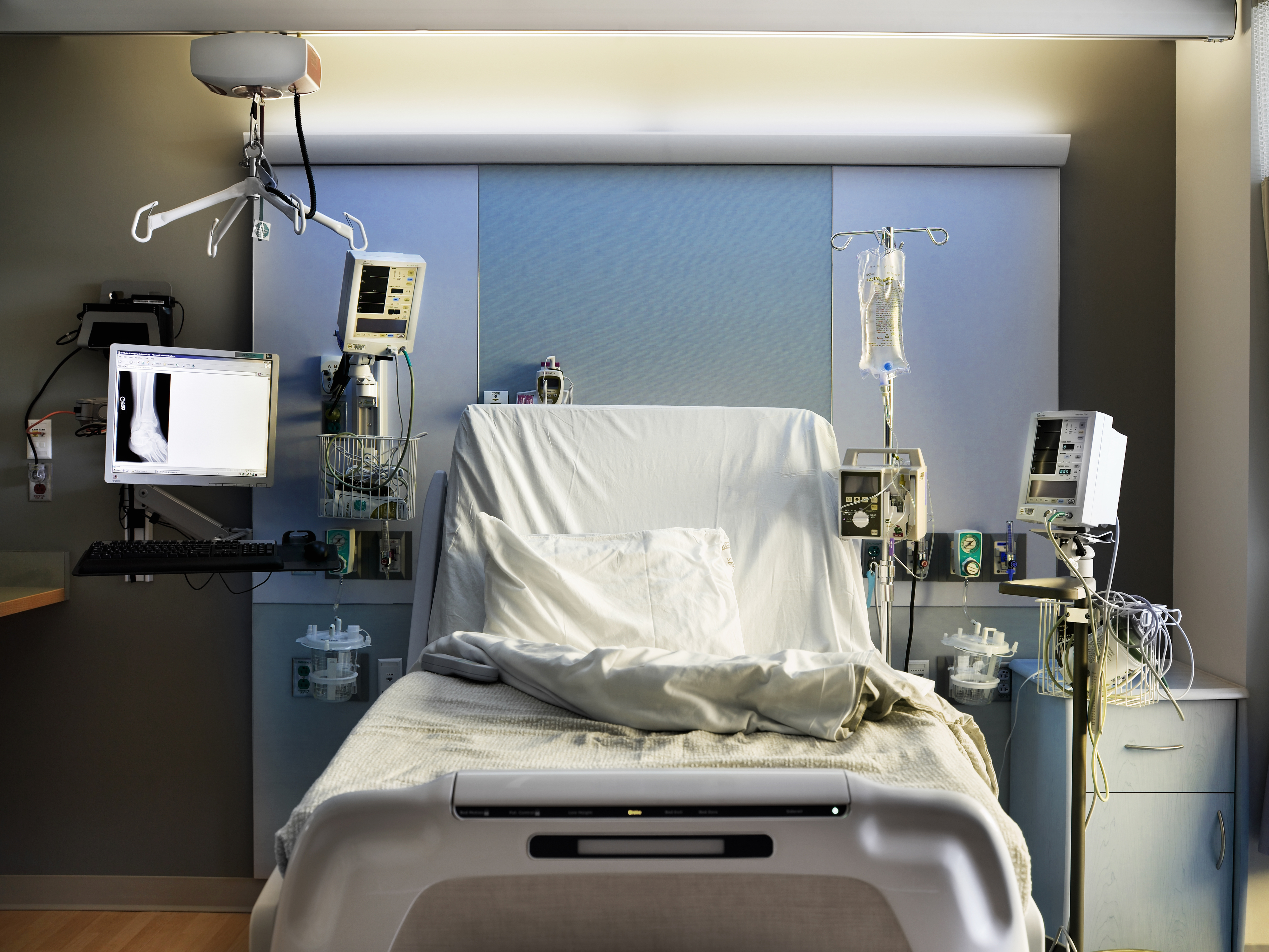 Empty hospital bed surrounded by medical equipment