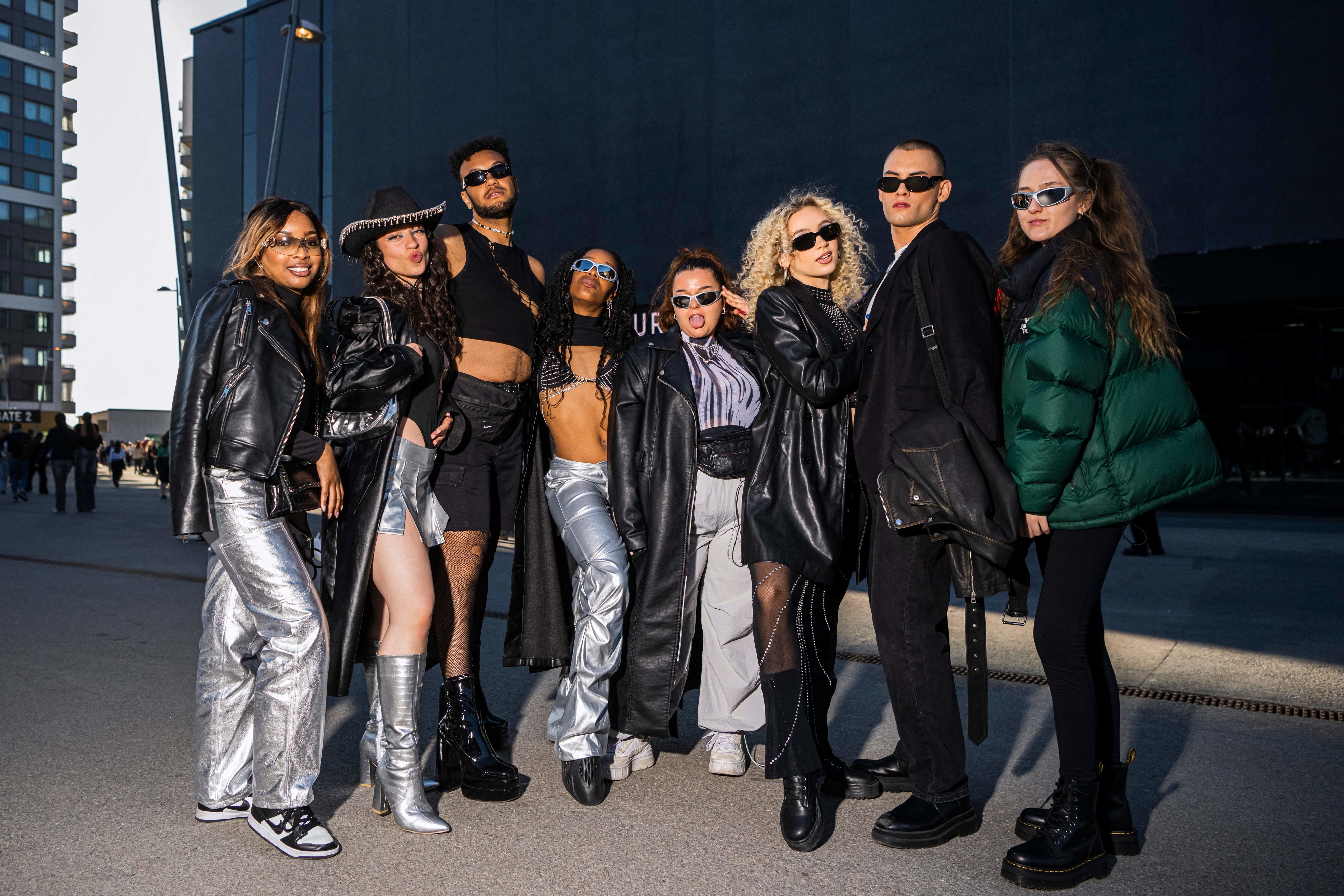 Eight people posing in sunglasses and various combos of silver and black clothing