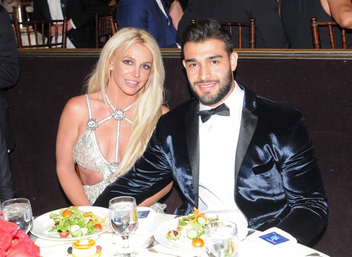 Britney Spears and Sam Asghari smile for a photo while sitting at a table with salads in front of them