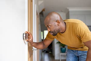 a person adjusts a smart thermostat