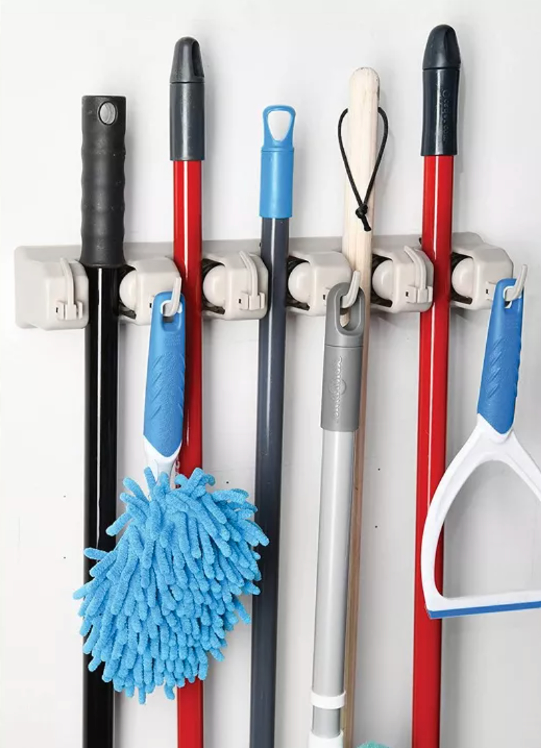 a mop and broom rack holding a variety of objects including a hand duster and a squeegee