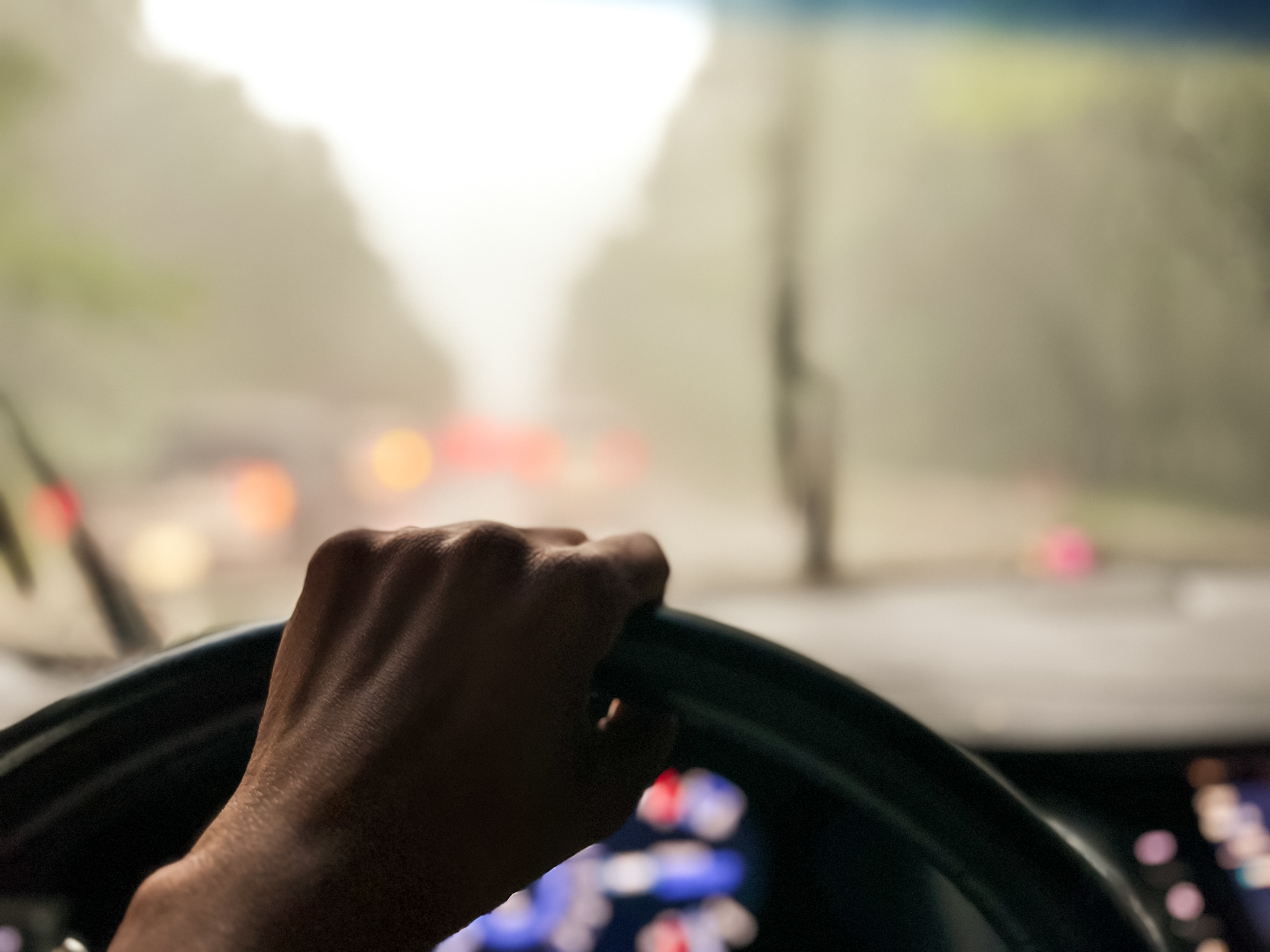 Someone&#x27;s hand on the steering wheel of a car