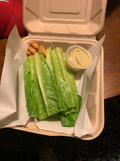 side caesar salad with a few leaves of whole romaine, croutons, and a side of dressing