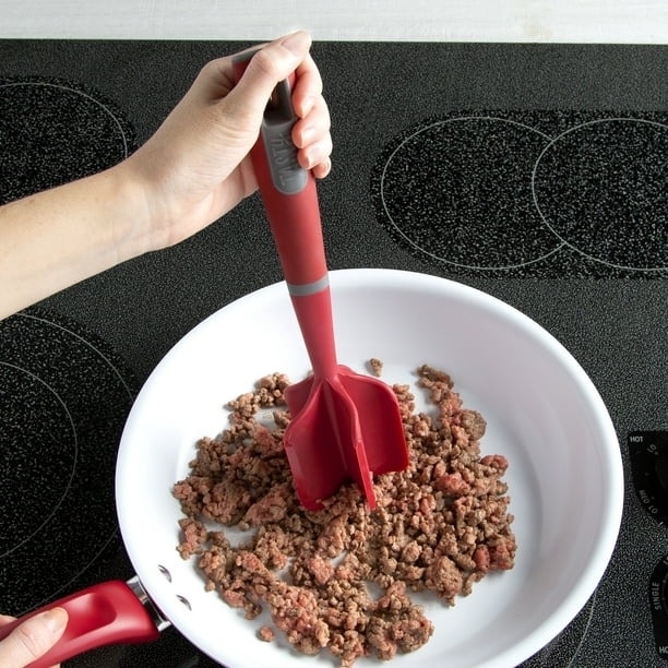 A meat mashing tool cutting up ground beef