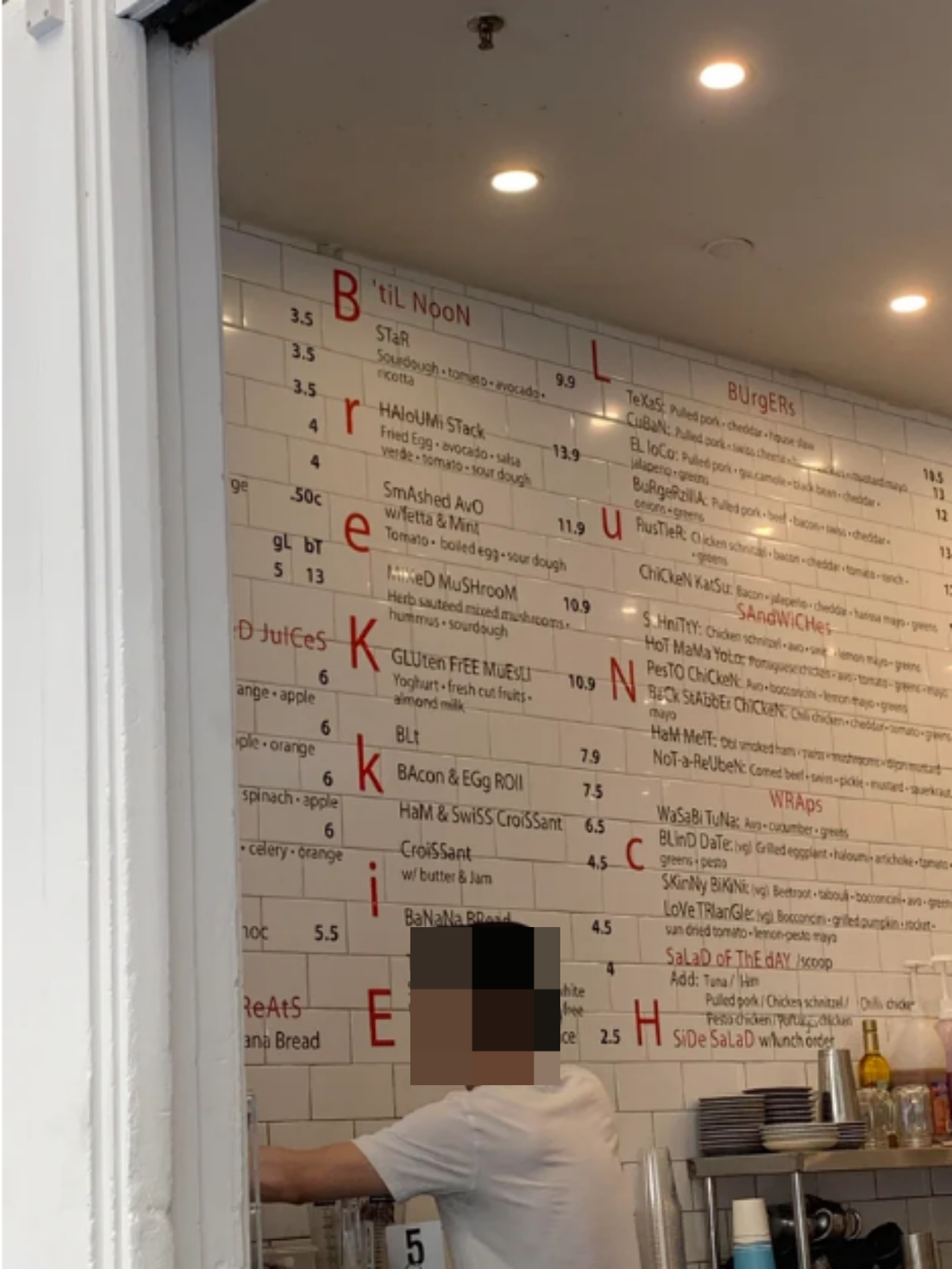 person working in front of giant menu on the wall of a restaurant