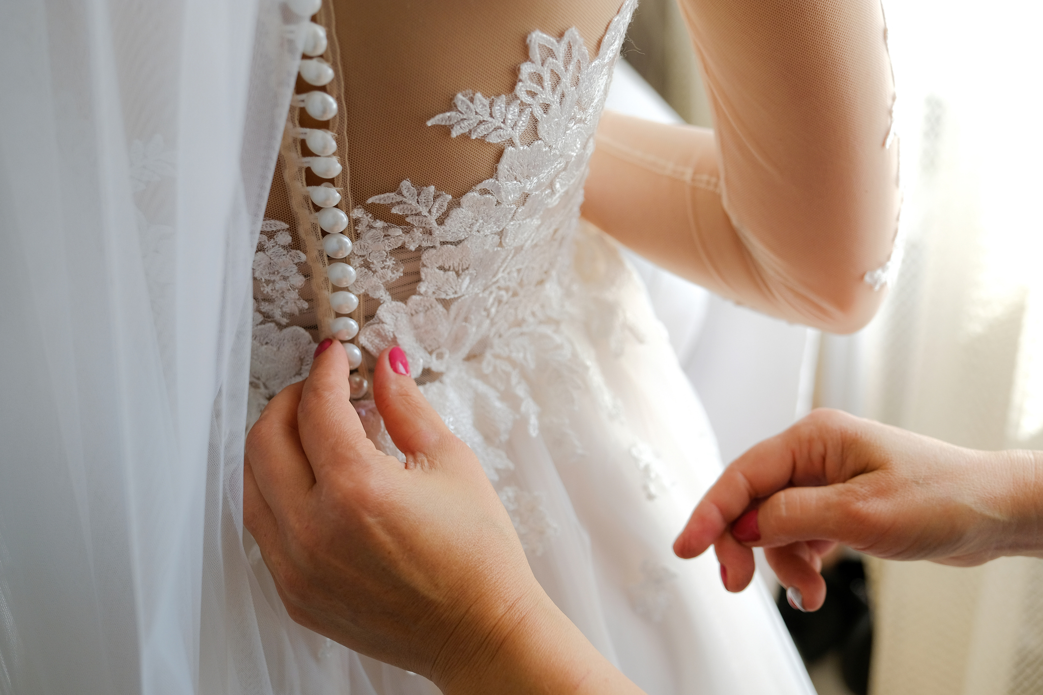 hands buttoning a wedding dress