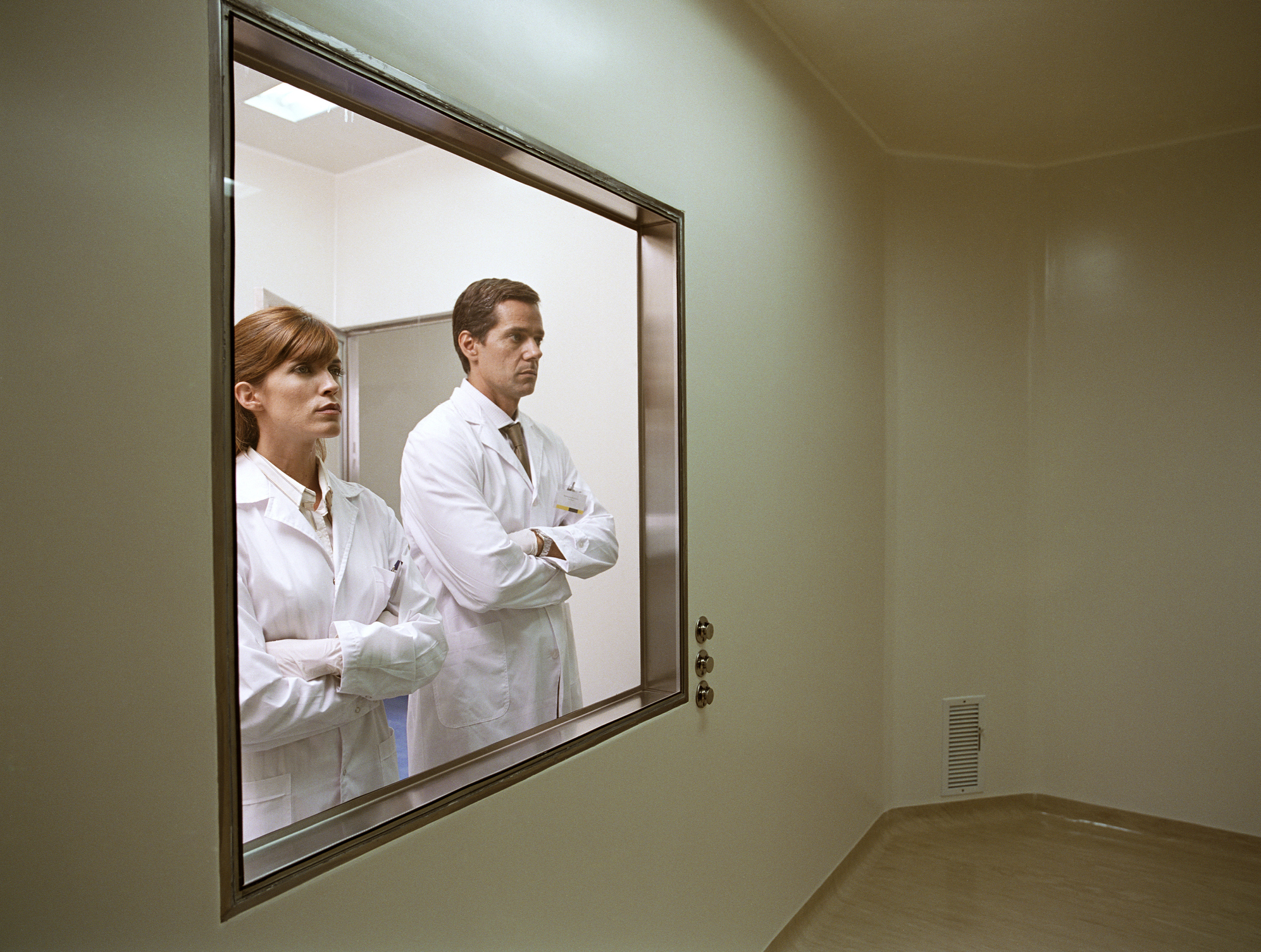 two people staring through a lab window