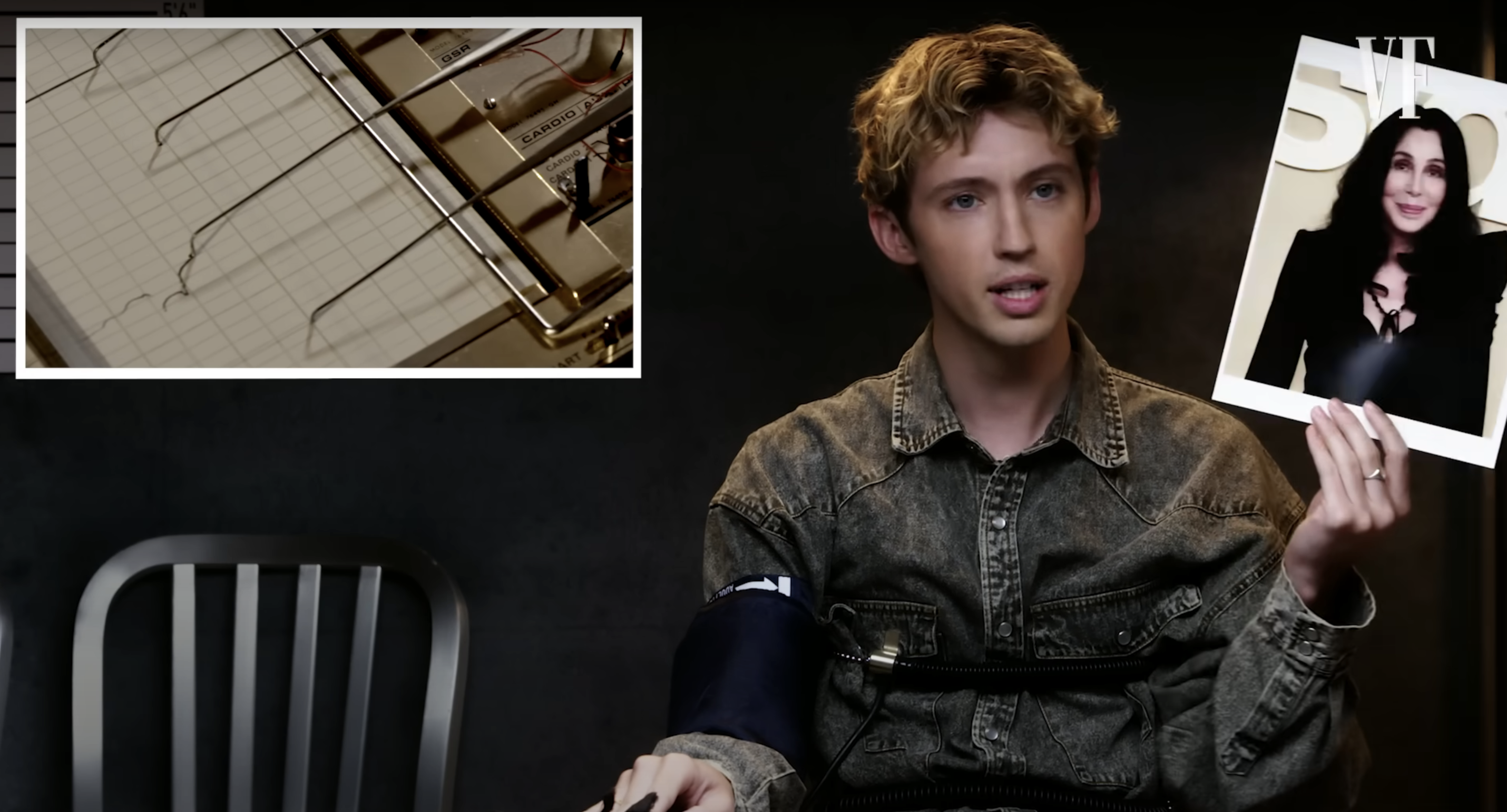 Close-up of Troye holding up a photo of Cher during the test