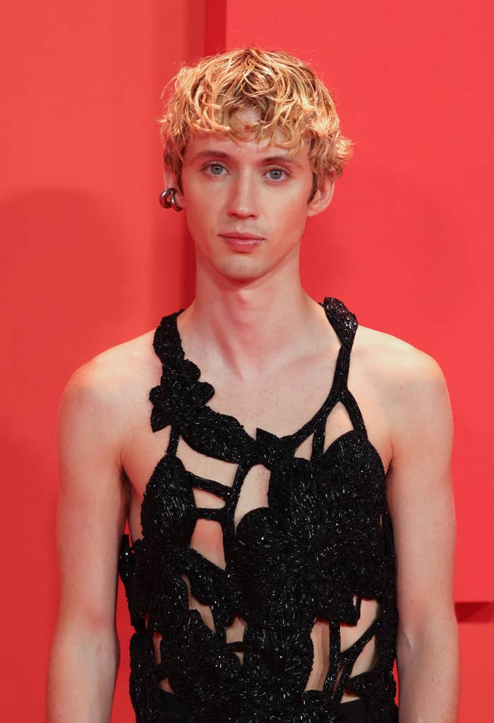 Close-up of Troye at a media event wearing a top with cutouts