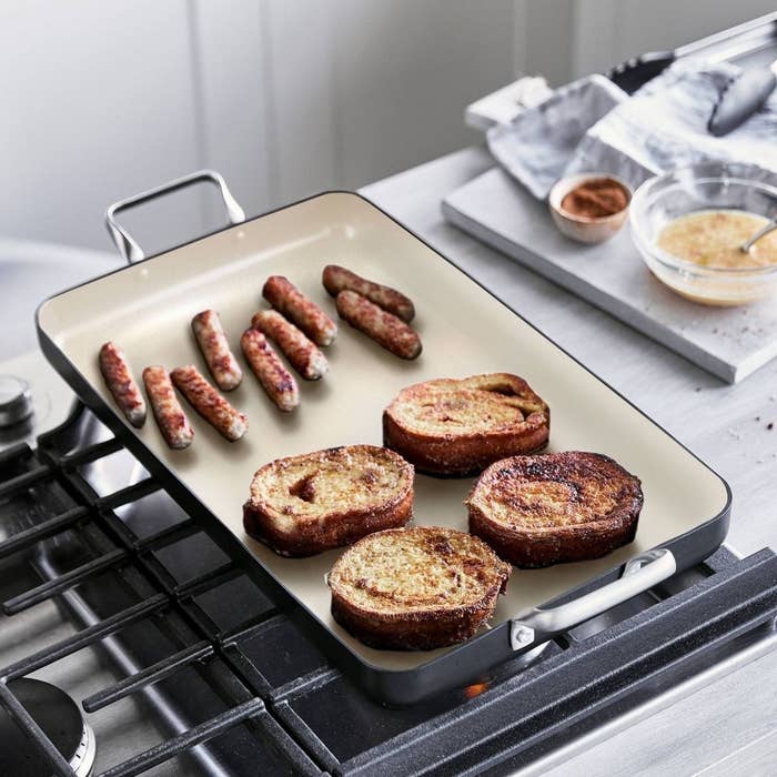 the double burner griddle on a stove cooking sausage and bread