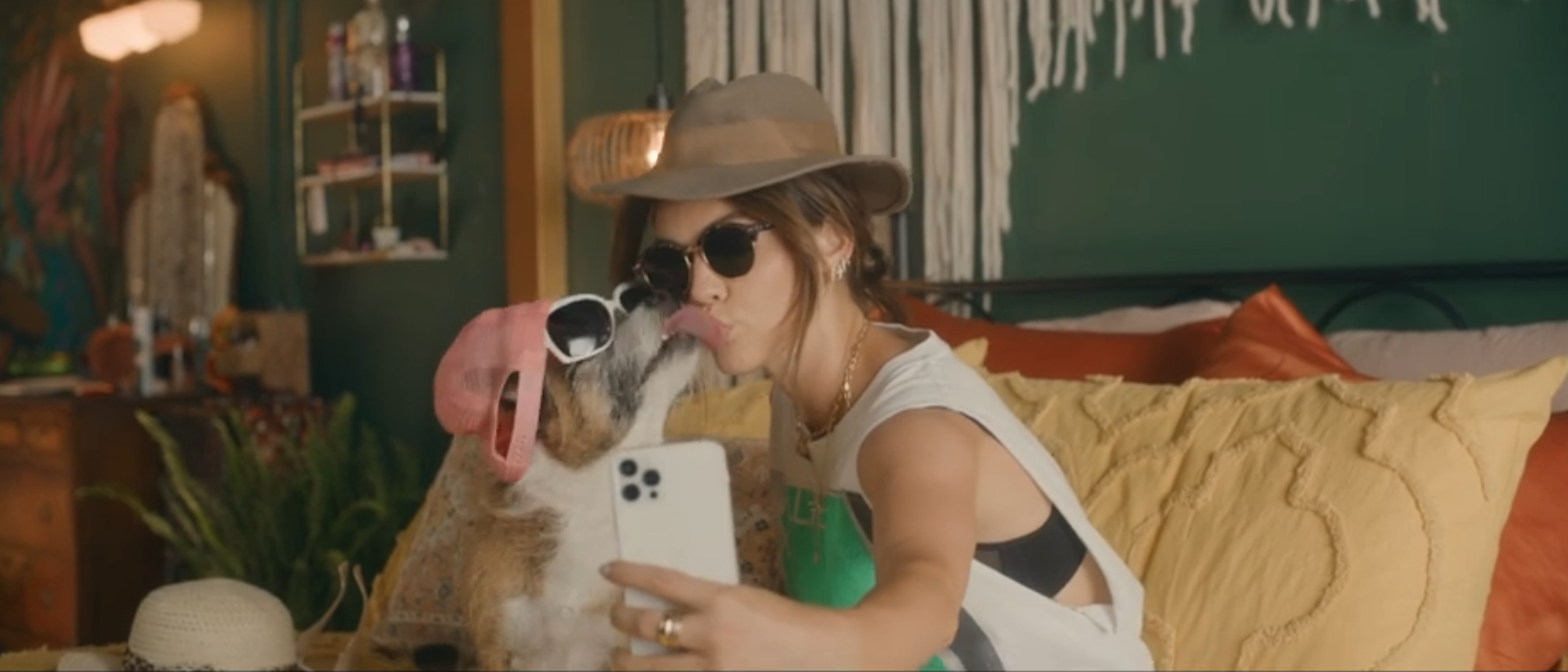 lucy hale taking selfie with dog in hat and sunglasses, it licks her face