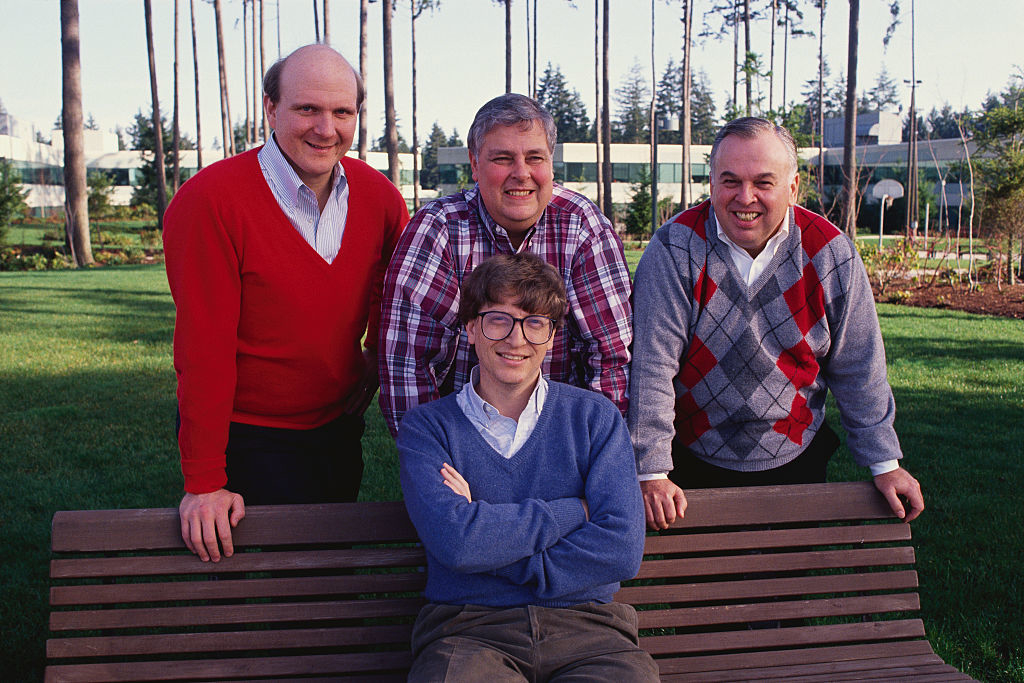 Men in sweaters smiling at a park bench