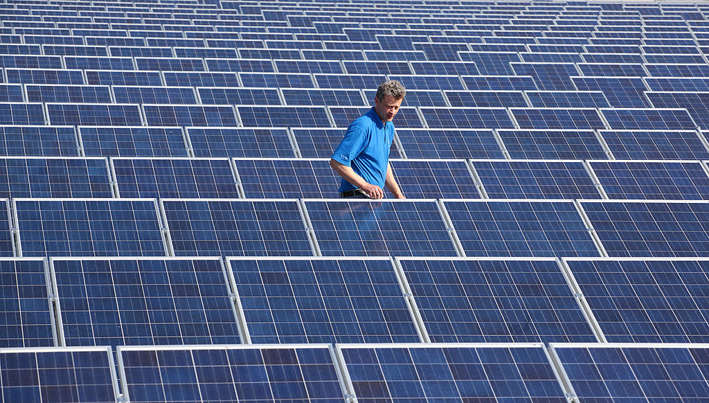 A man standing amongst solar panels