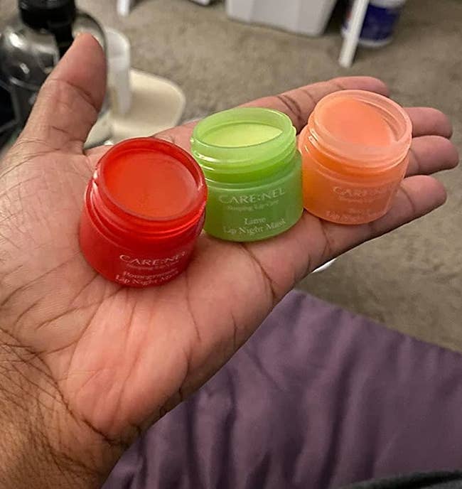 A reviewer holding the mini jars in red, green, and pink