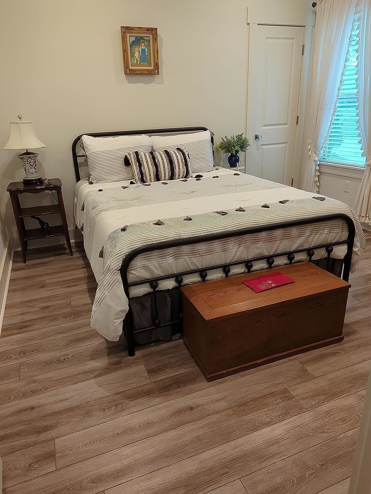 Reviewer image of the black metal bed frame paired with neutral colored bedding