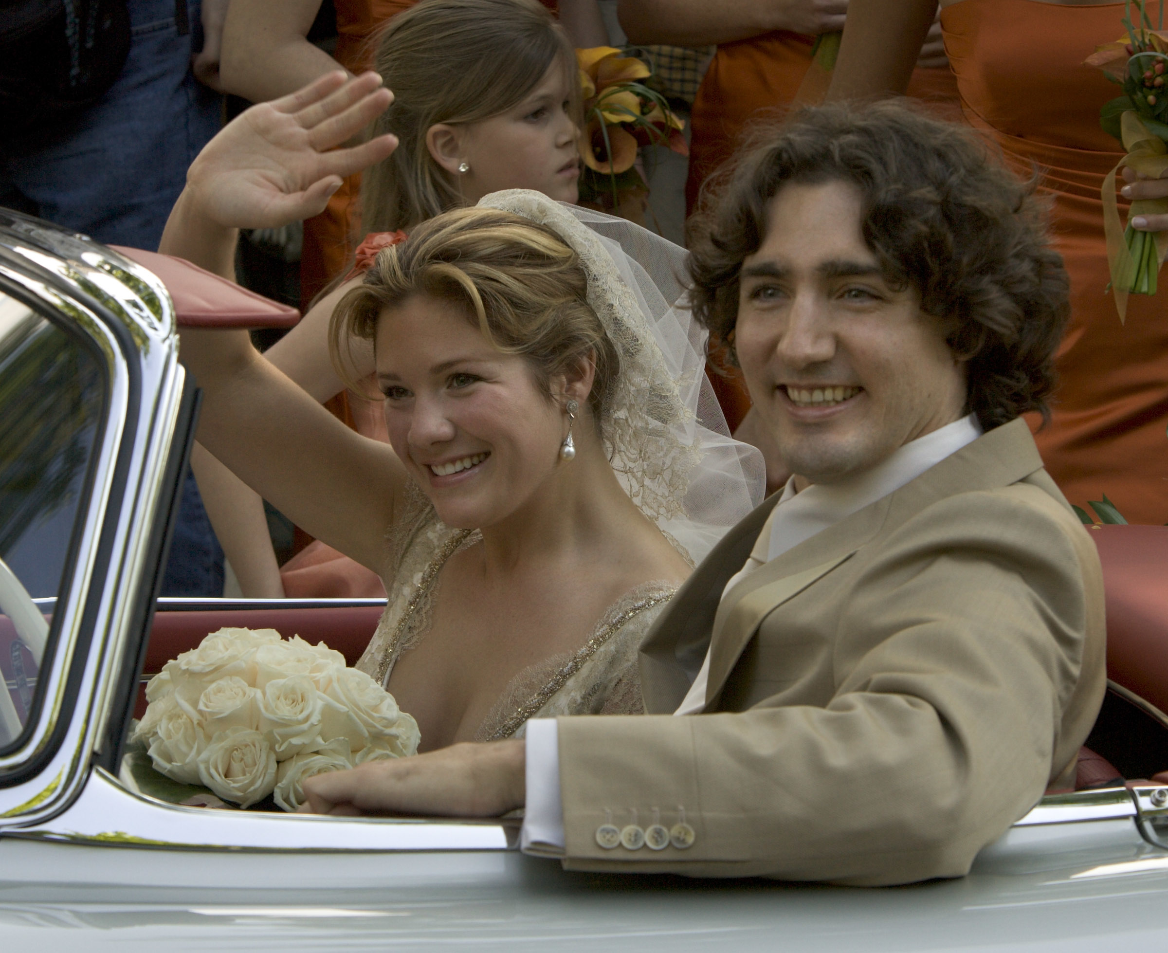 closeup of the newlyweds driving off in a convertible