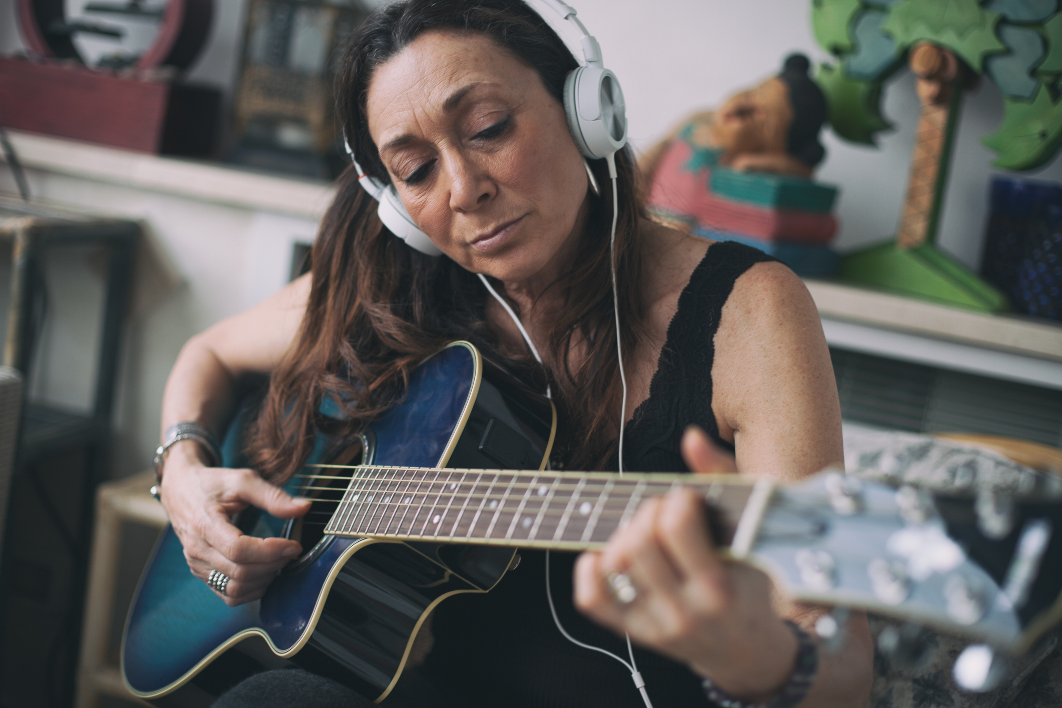 A woman wearing headphones and playing the guitar