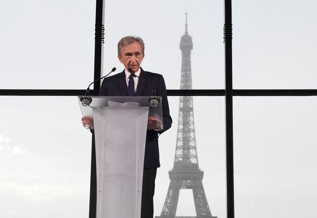 him speaking at a podium with eiffel tower behind him