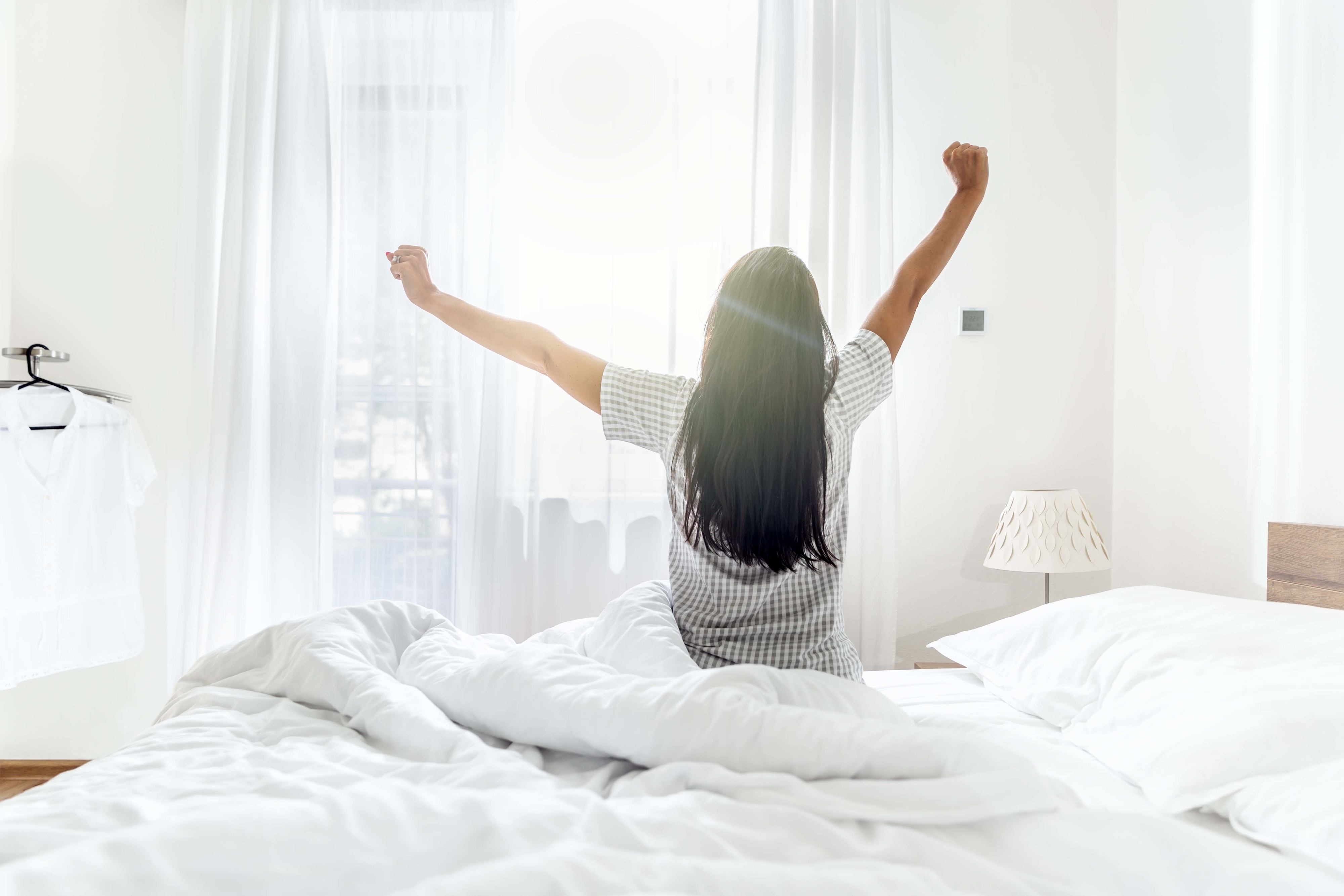 A woman stretching as she gets out of bed in the morning