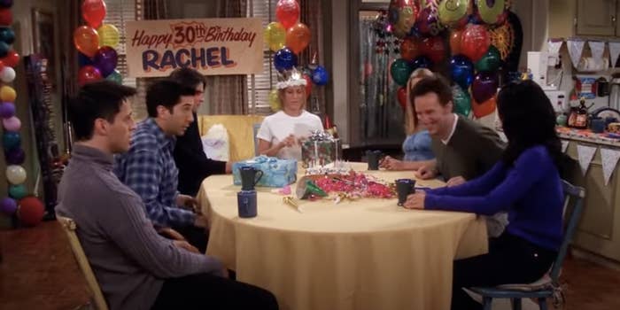 the cast of friends sitting on a table