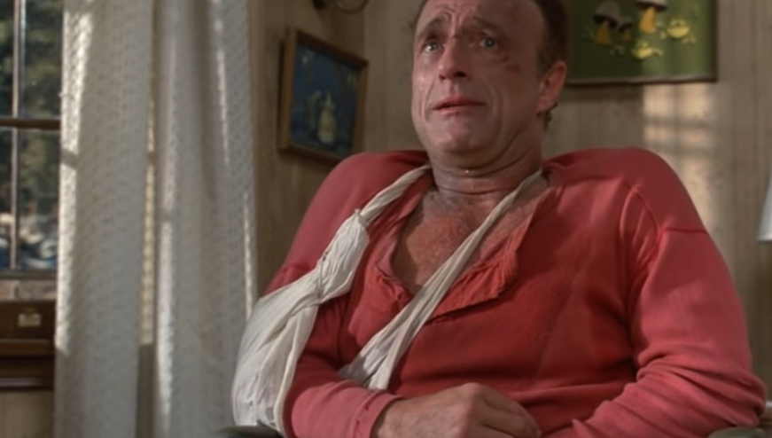 James Caan as Paul Sheldon with his arm in a sling, looking stressed