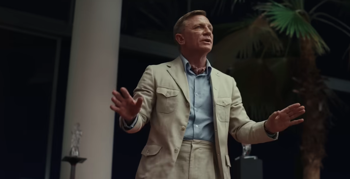 Daniel Craig as Benoit Blanc talking to a group of people in Glass Onion