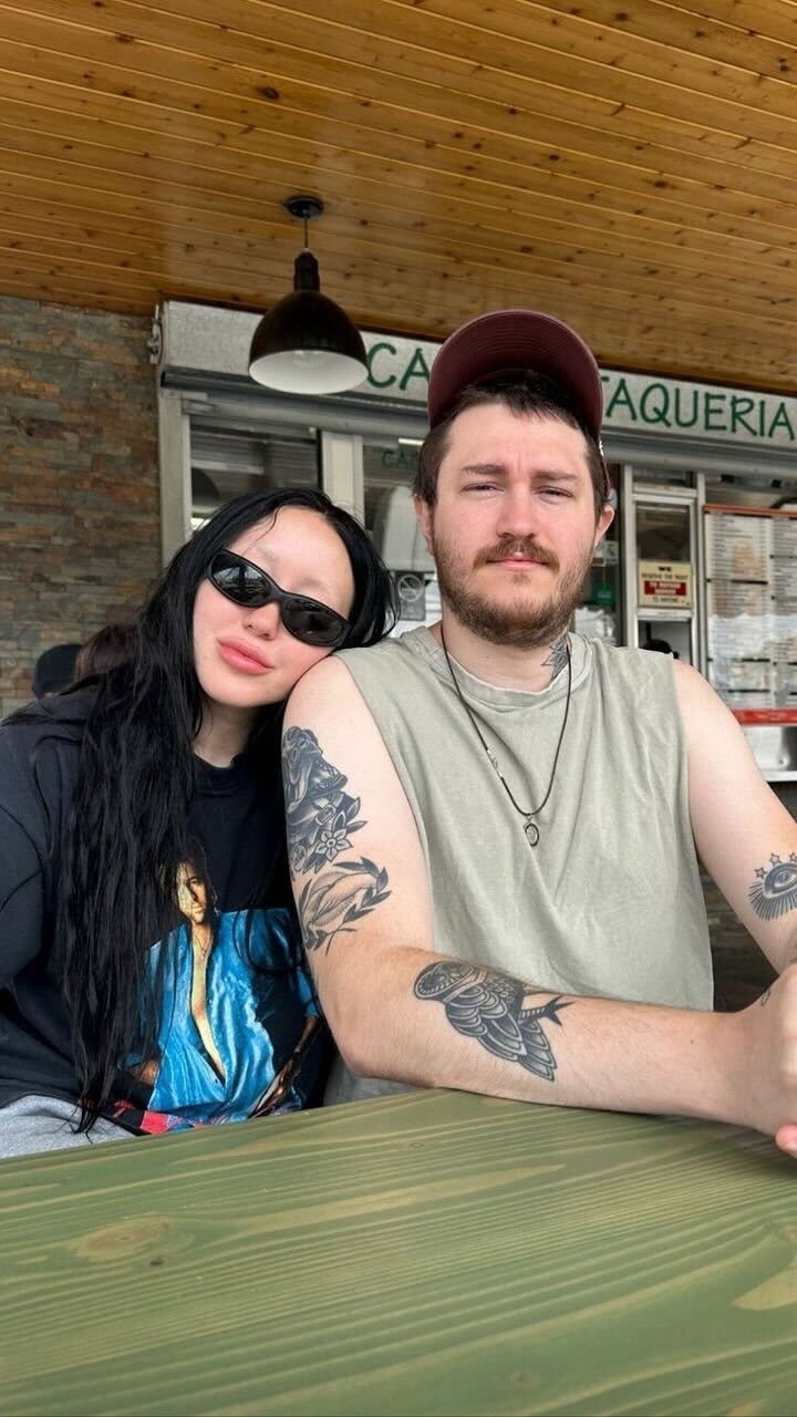 A closeup of Noah in a shirt with her dad on it as she leans on her brother Braison&#x27;s shoulder