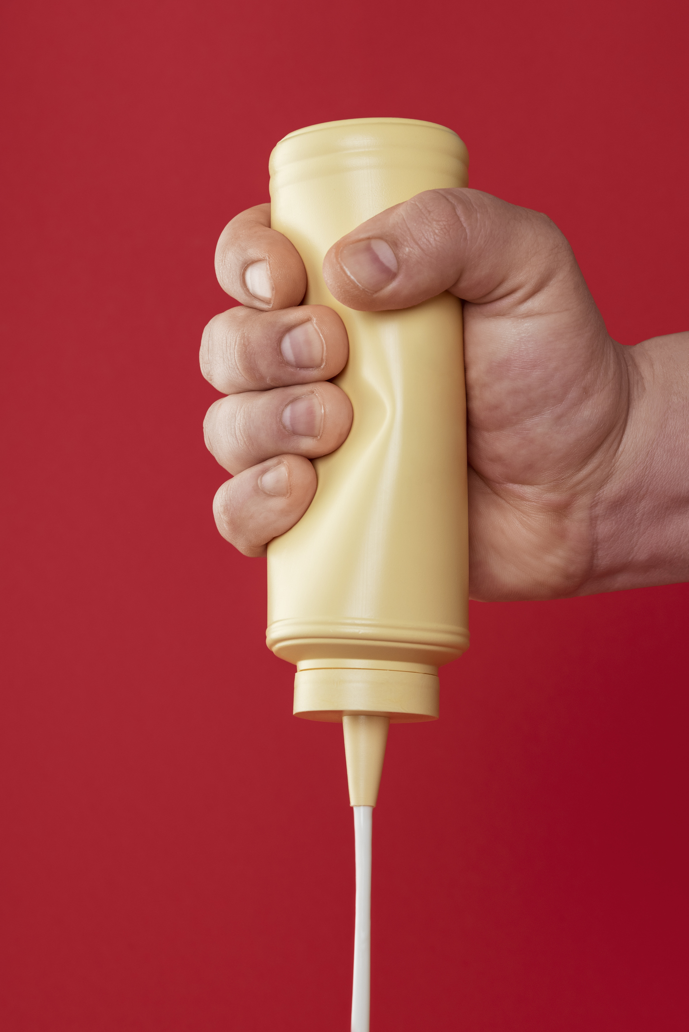 A hand squeezing a bottle of mayo