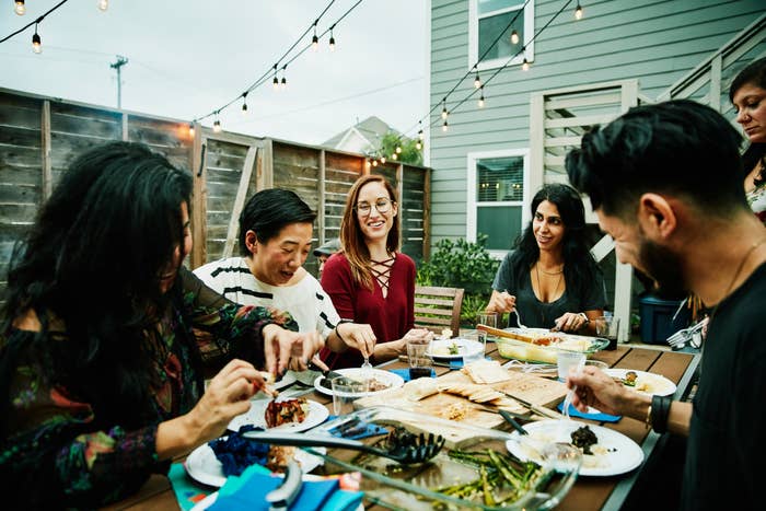 people of different races hanging out around a table, having a cookout