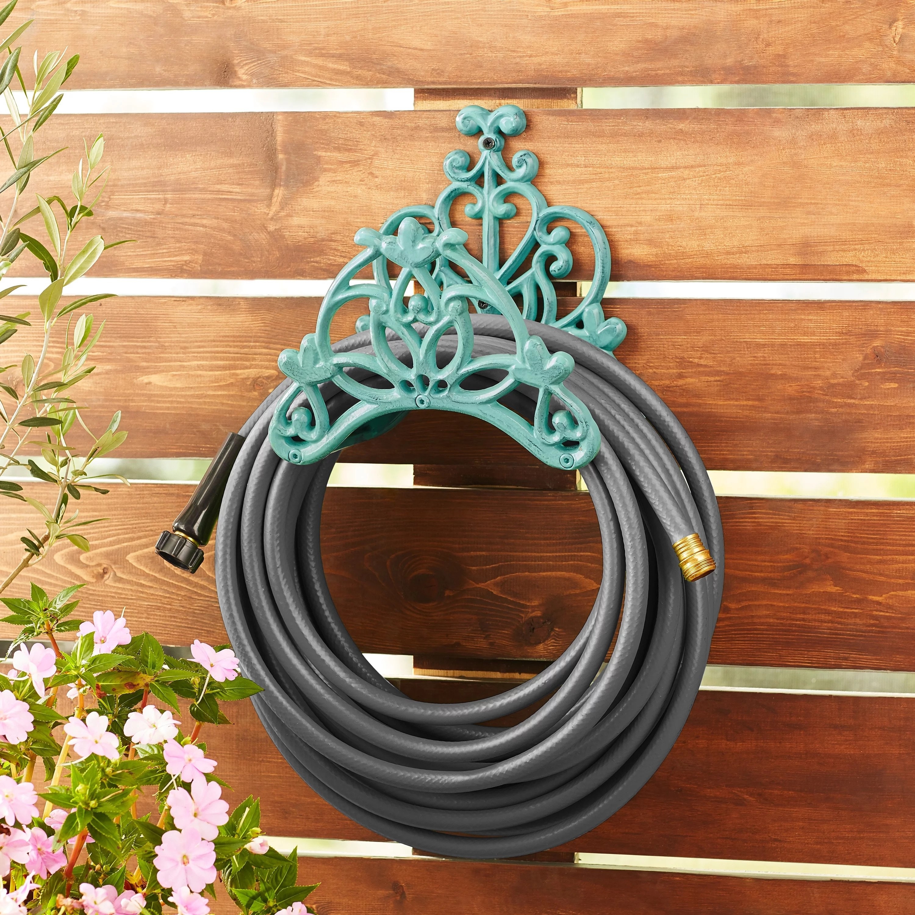 The teal iron-wrought hose hanger mounted on a wall
