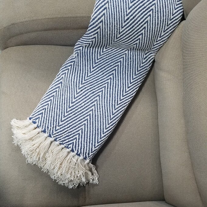 a reviewer photo of the blanket with a chevron pattern on a couch