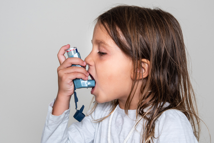 A young girl using an asthma inhaler