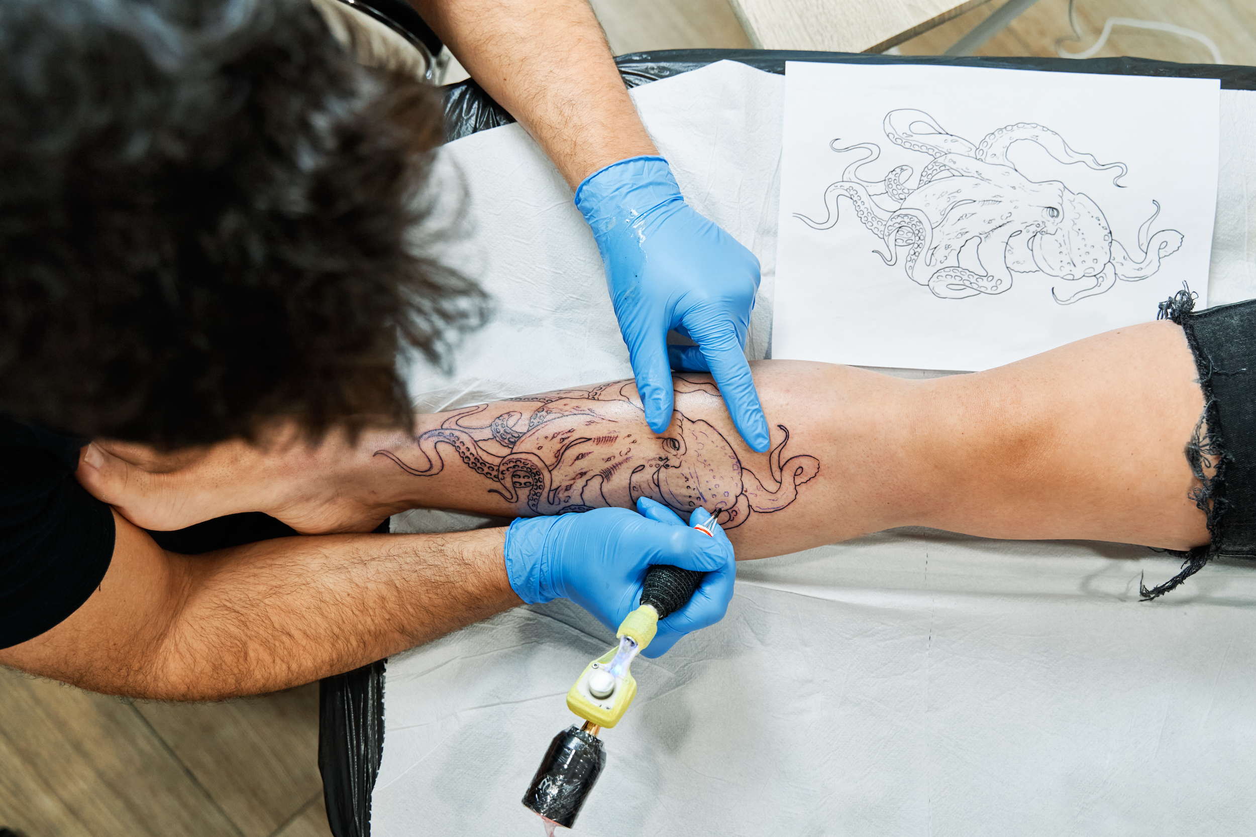 A tattoo artist working on a customer