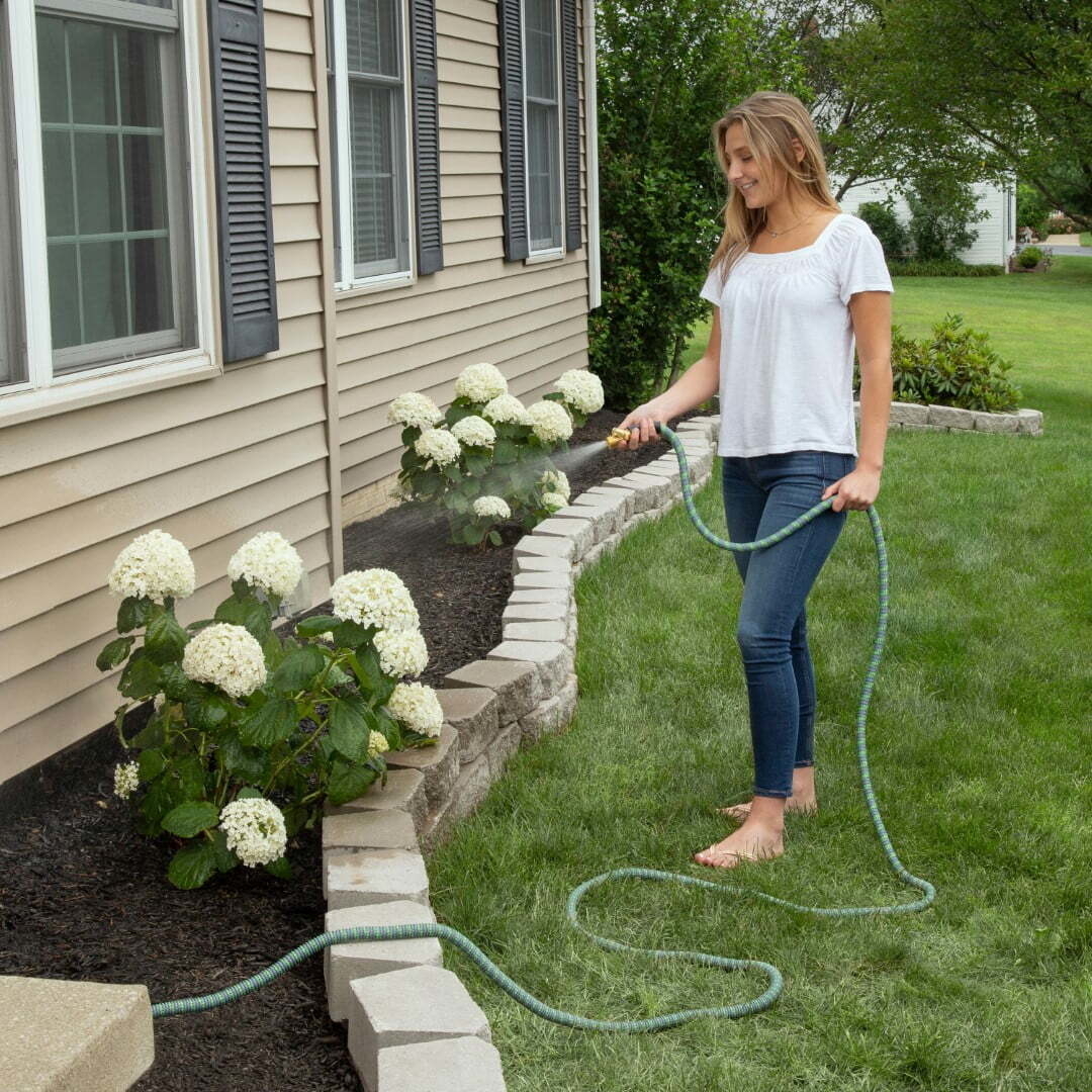 A person watering flowers using the hose