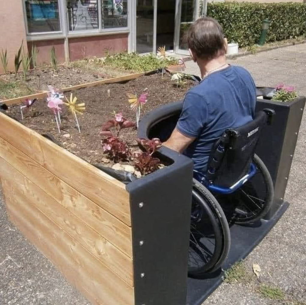 person in a wheelchair rolled up to the raised garden