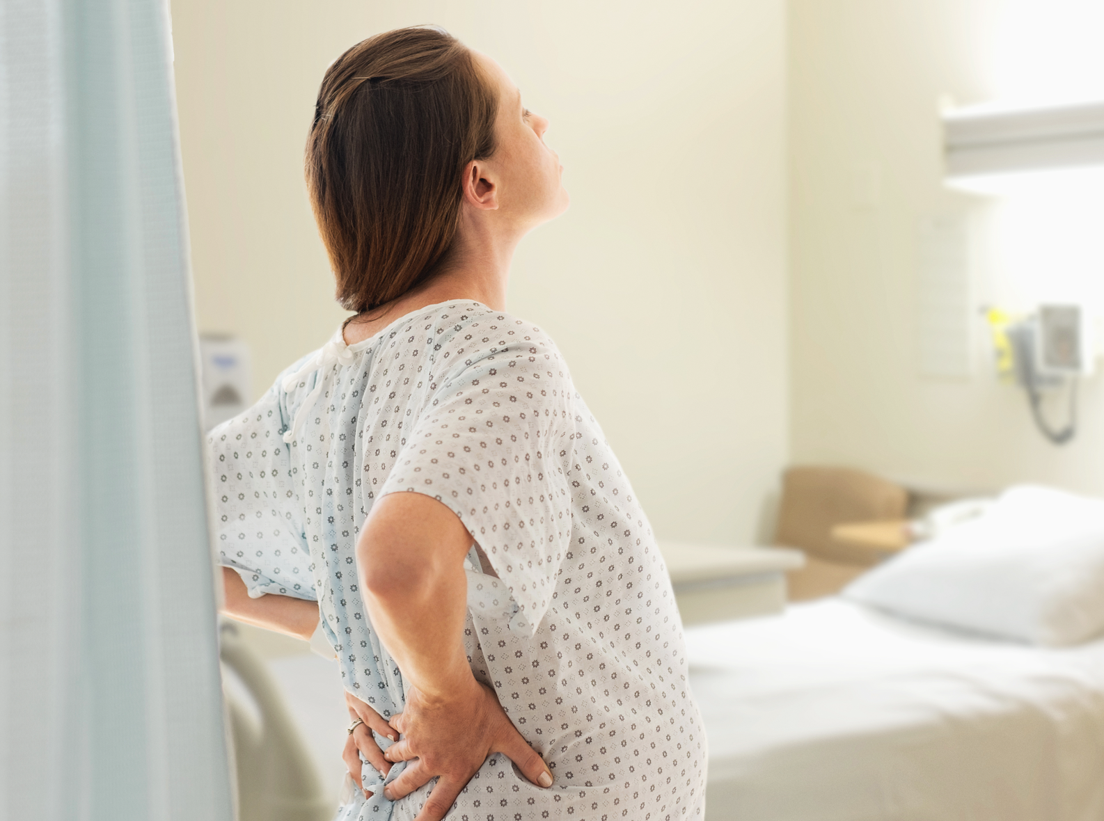 Woman standing in hospital room while pregnant