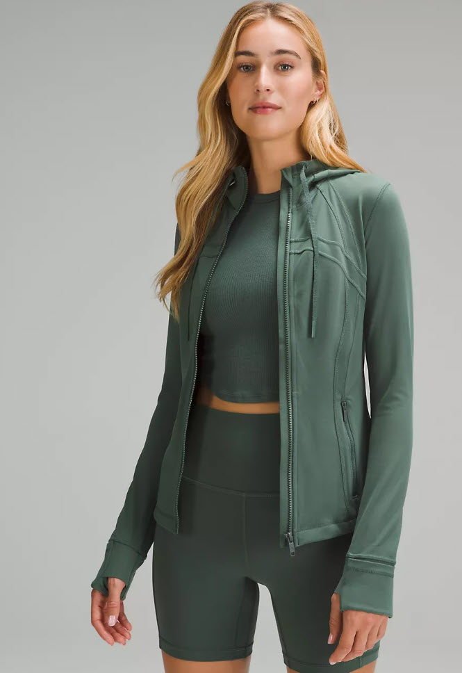 model in a dark green zip up jacket, top and shorts set
