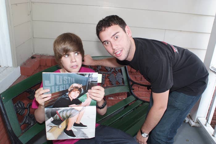 Scooter Braun leaning down towards a younger Justin Bieber who&#x27;s holding a poster of himself