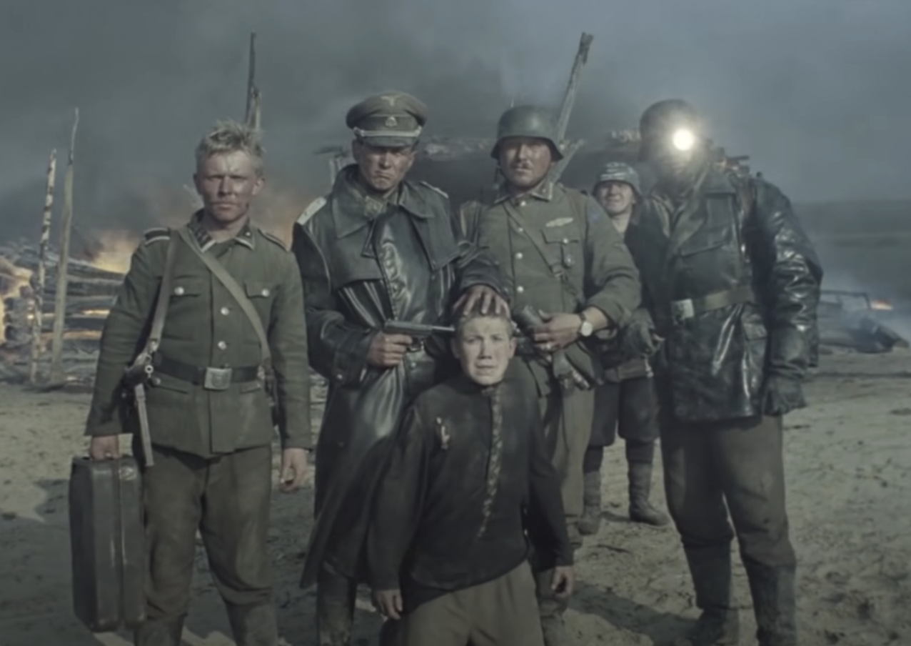 Soldiers in a war scene, with one holding a gun to a boy&#x27;s head