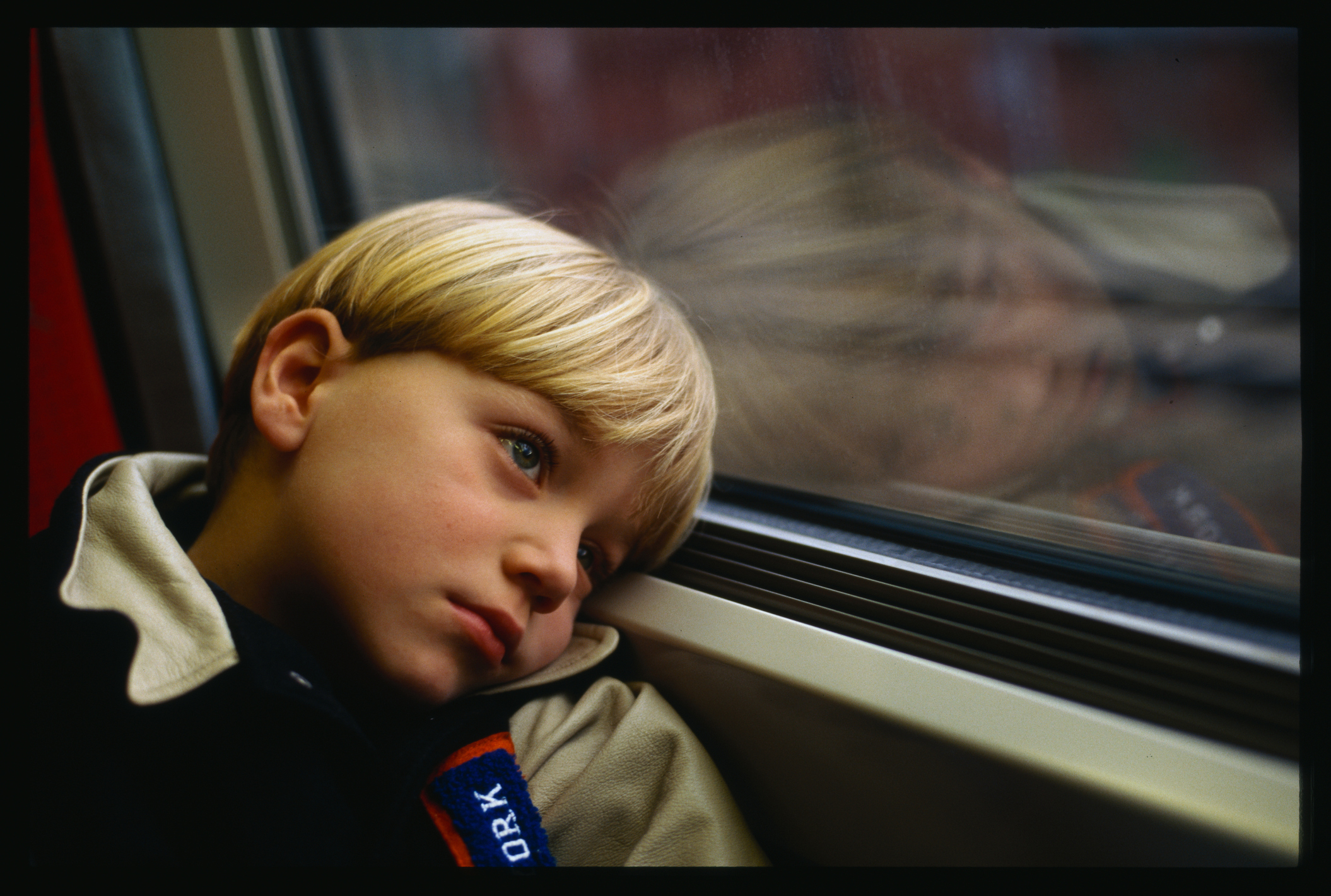 A little boy looking bored on a train