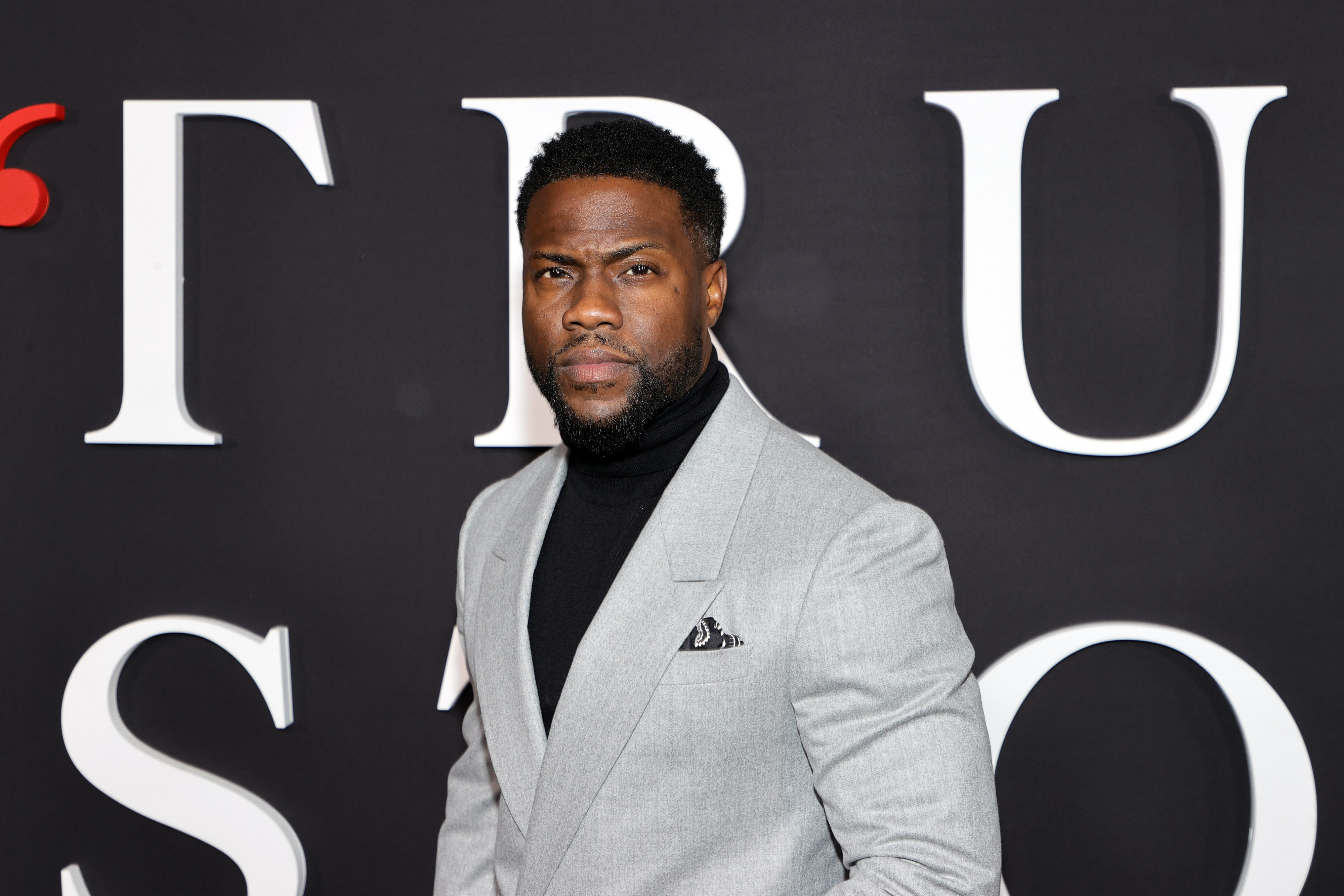 Close-up of Kevin in a turtleneck and suit at a media event