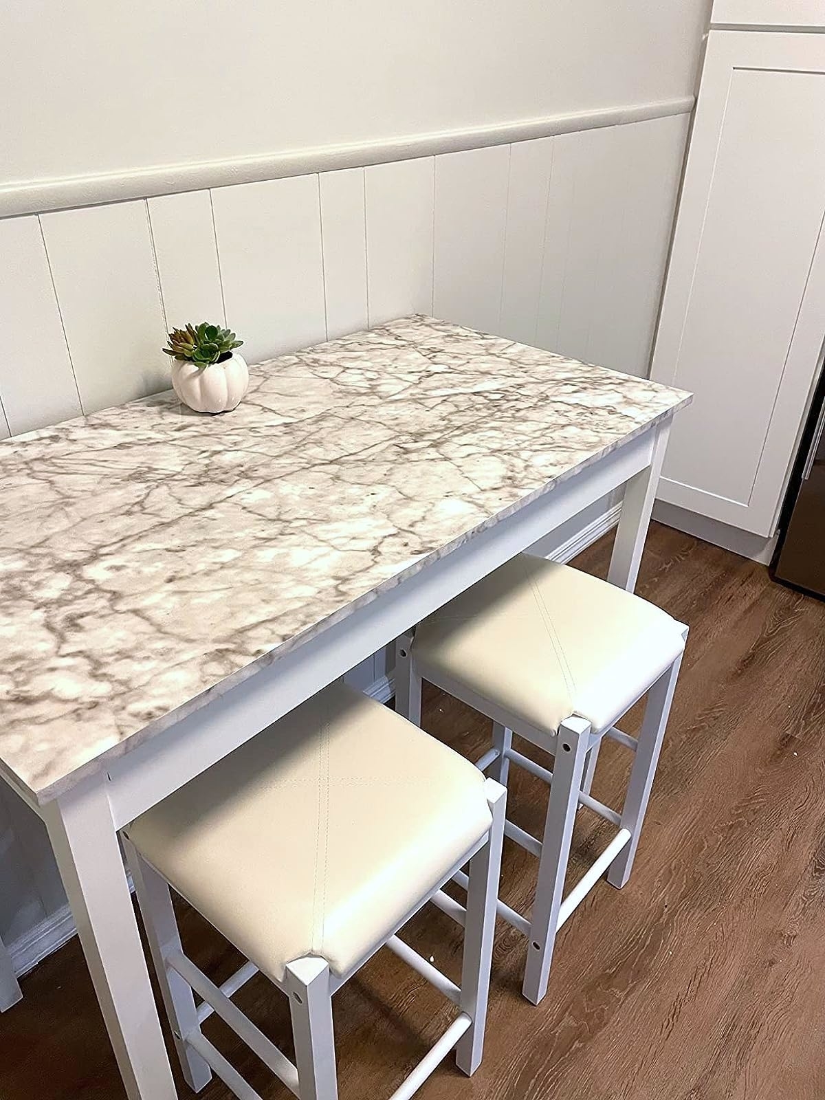 Reviewer pic of the tall table in white with a marble-like top and two stools under it, also in white