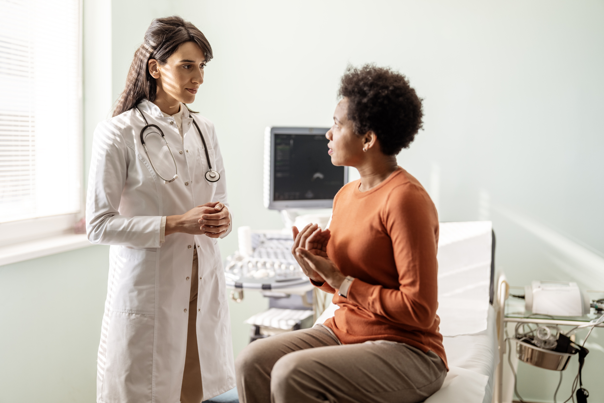 A female doctor talks with her patient sitting on a doctor&#x27;s chair