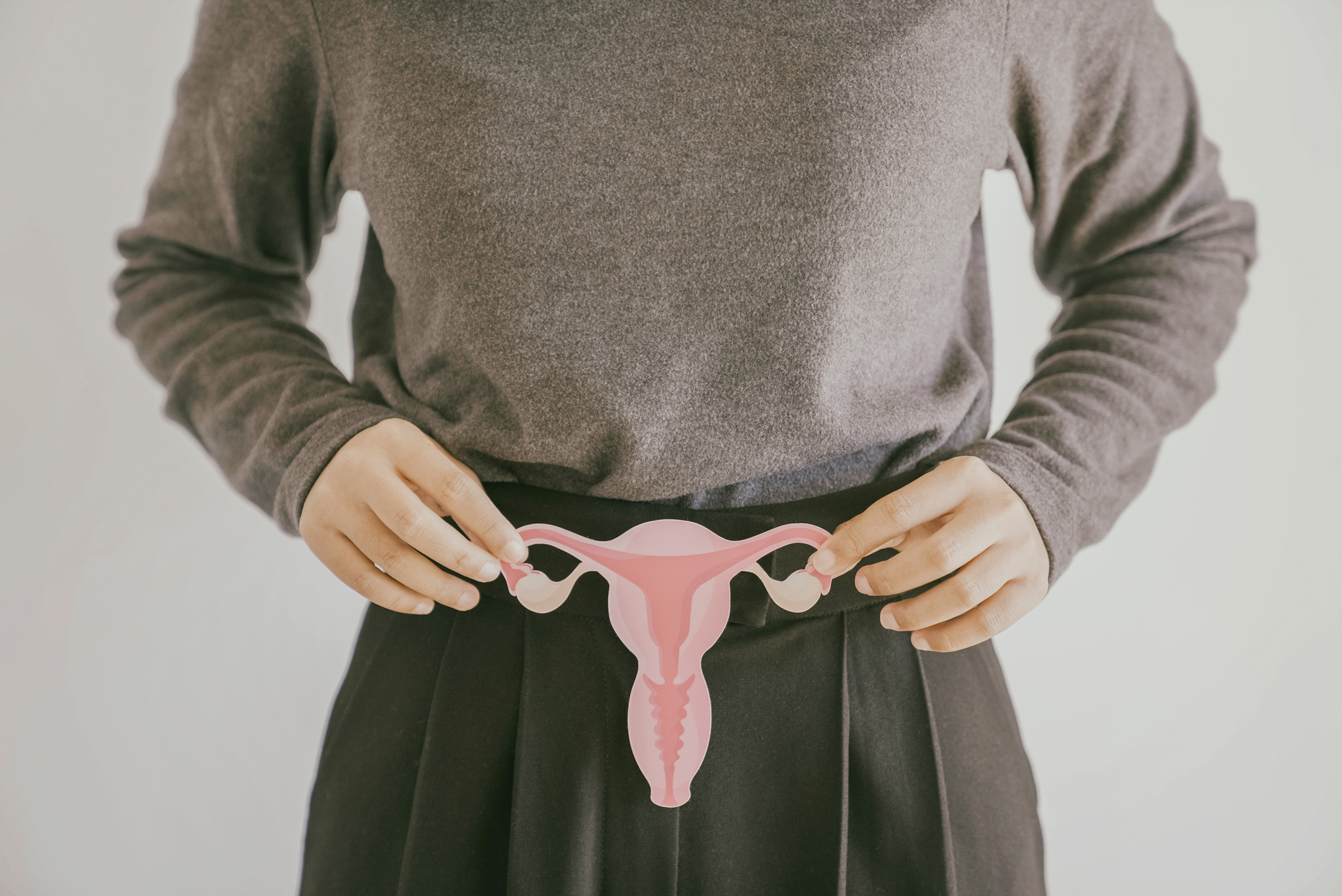 Hands holding a paper cutout of the uterus, female reproductive system