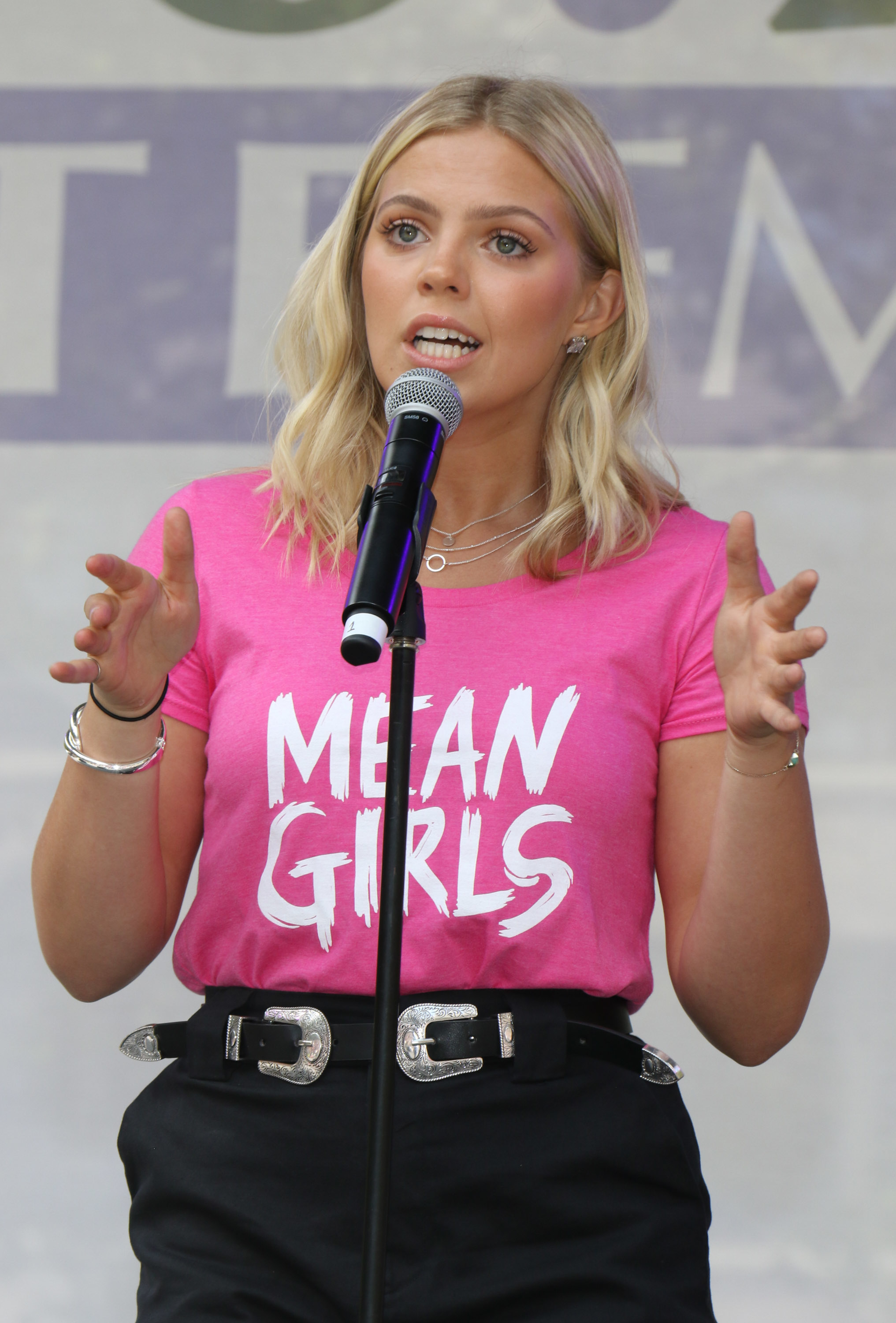 Closeup of Reneé Rapp talking into a mic wearing a shirt that says &quot;Mean Girls&quot;