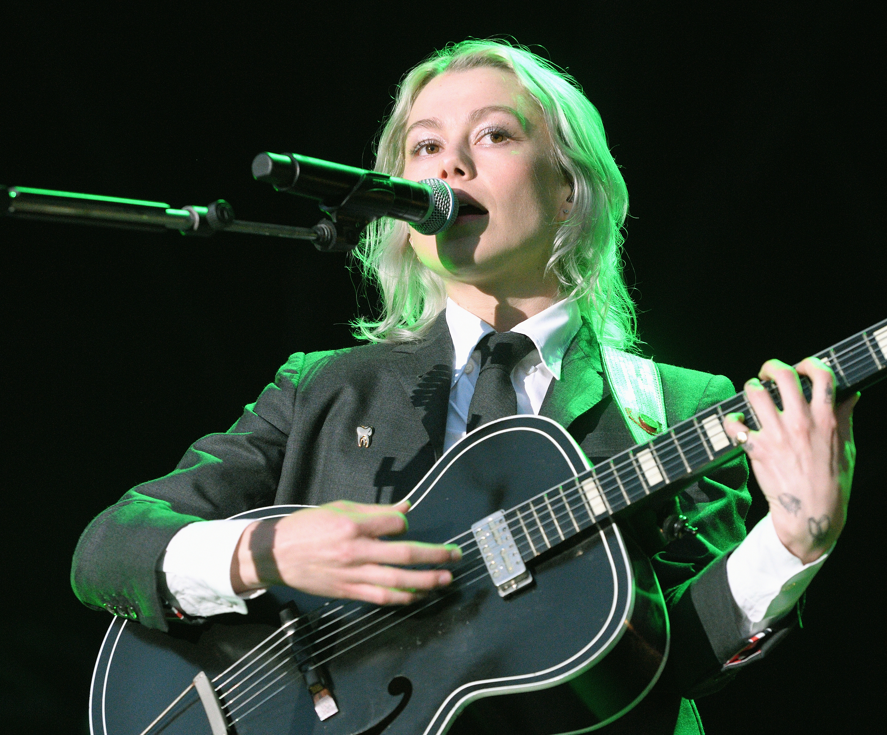 Phoebe onstage singing and playing guitar