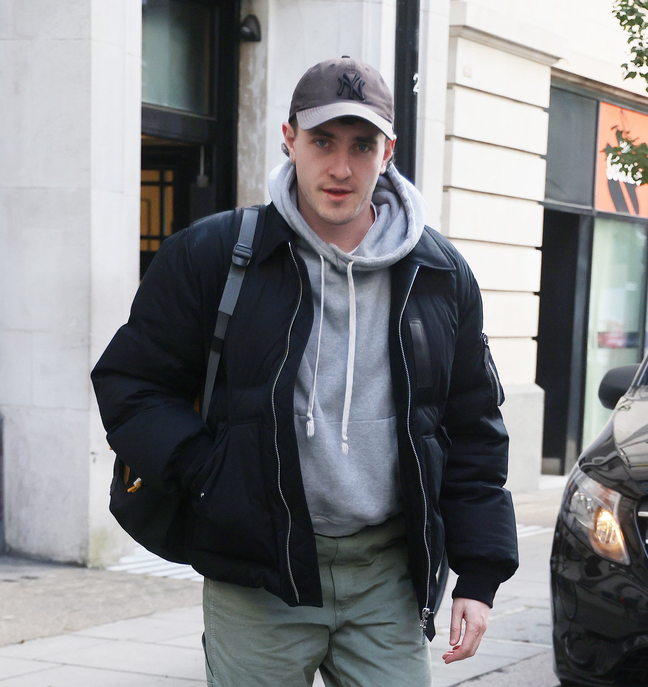 Paul Mescal walking outside in a baseball cap