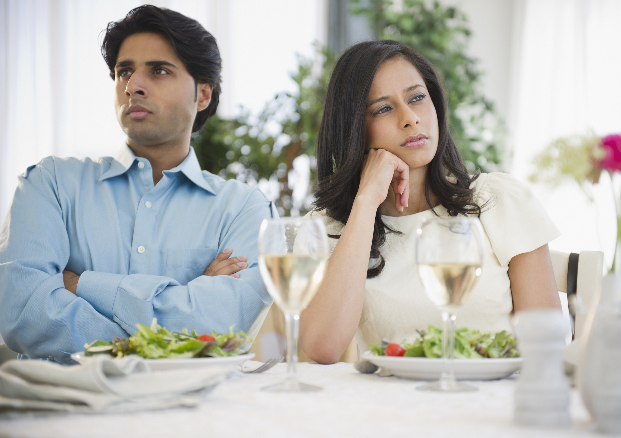 Two bored, upset people sitting at a dining table