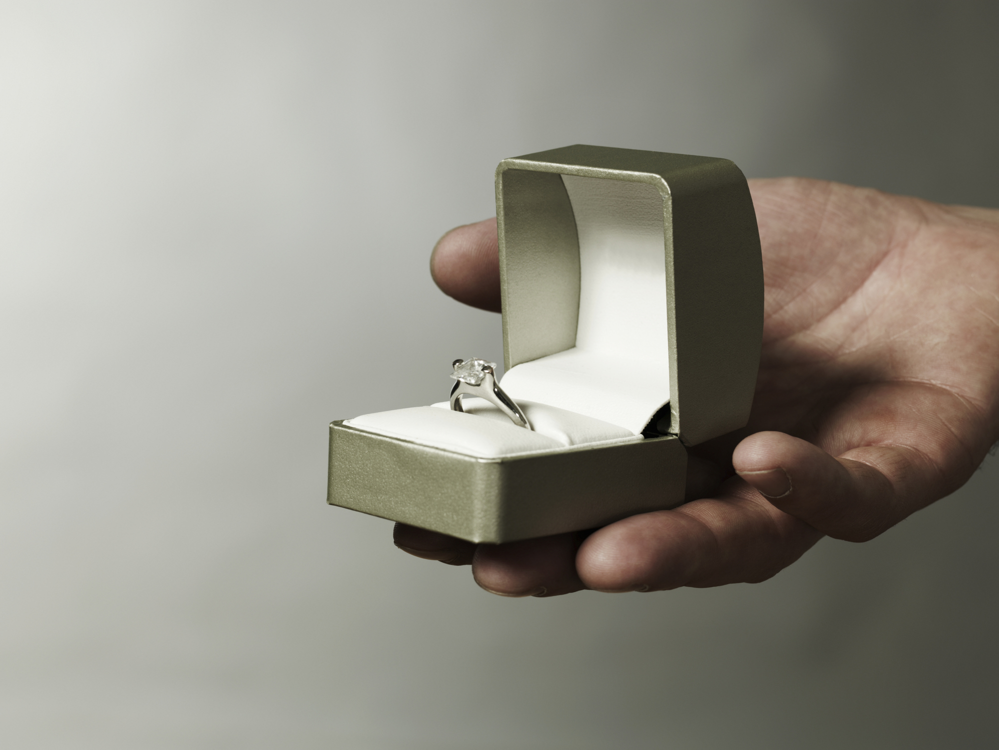 A person holding an engagement ring in a box